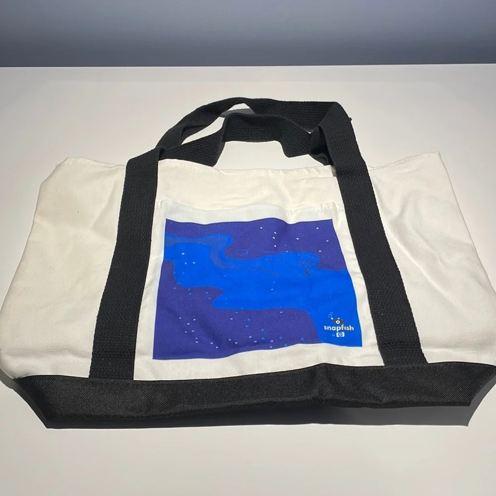 Canvas tote with black straps. Outside pocket with Snapfish logo. NWOT